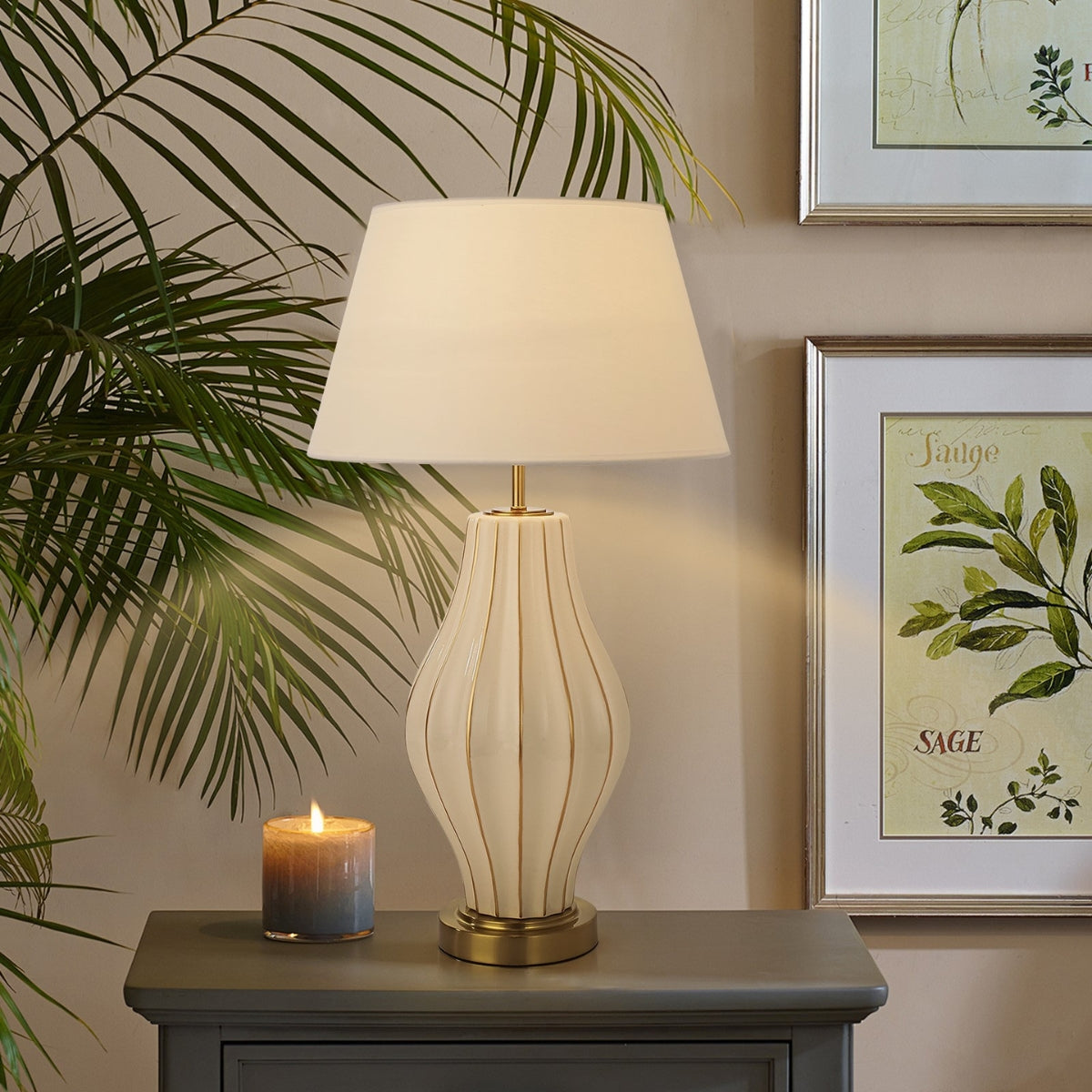 Table lamp on a side table with a candle and framed artwork in the background