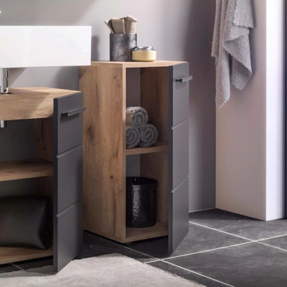 Bathroom setup with wooden vanity, storage unit, and towels.