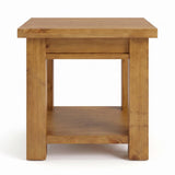 Ailbhe rustic oak side table with a warm honey finish, featuring an open lower shelf, and thick blocky legs, shown against a plain white background.