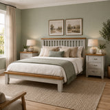 A styled bedroom scene featuring the Canter grey wood bed frame with white bedding, beige and sage green pillows, flanked by two matching grey nightstands with lamps, set against a sage green wall.