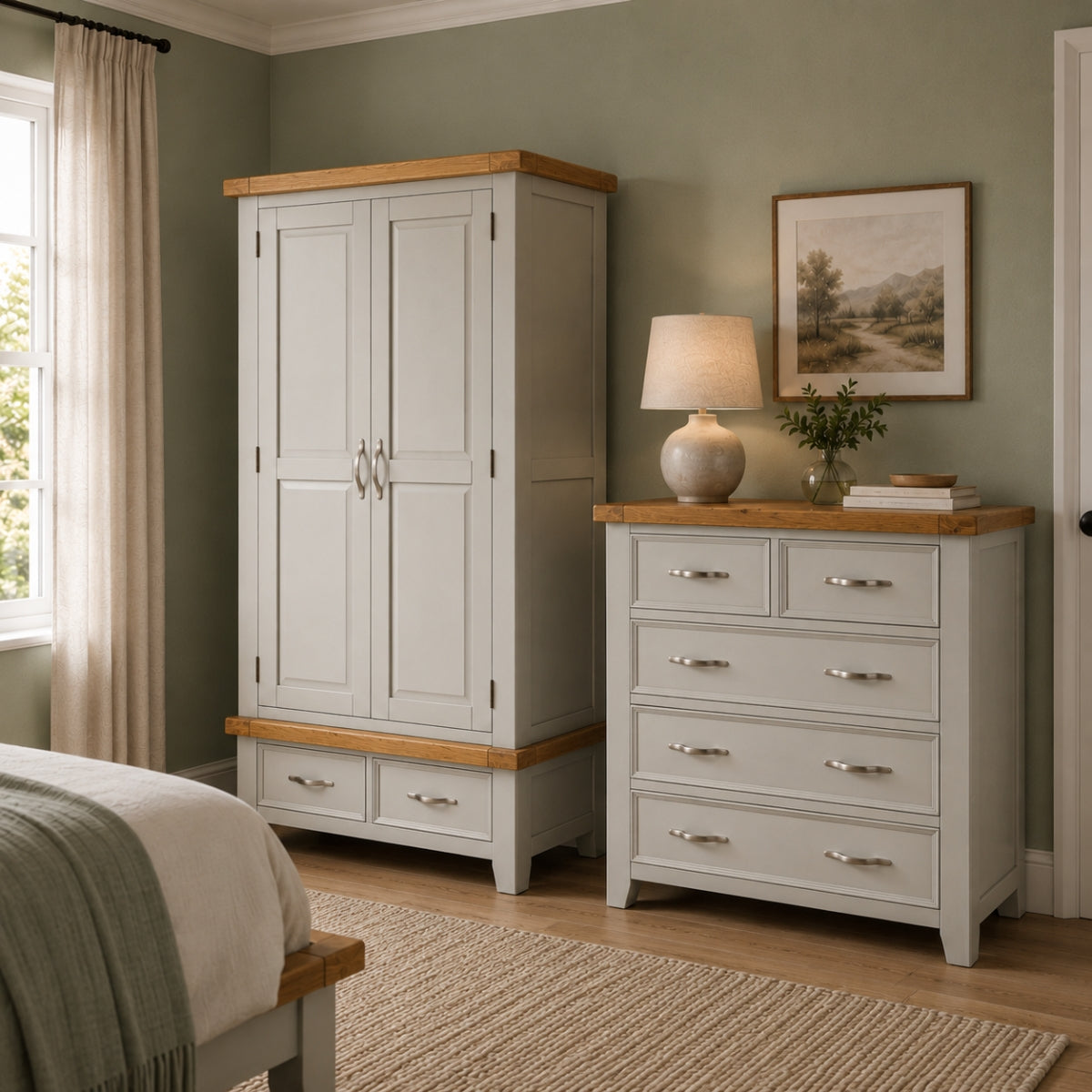 Canter grey bedroom set featuring a tall double-door wardrobe and a matching five-drawer chest, both in a grey finish with natural oak tops and bases. The furniture is styled in a bedroom with sage green walls, a window with beige curtains, a woven rug, and a bedside table lamp.