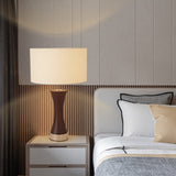 Bedroom with a lamp on a nightstand and a bed with pillows against a striped wall.