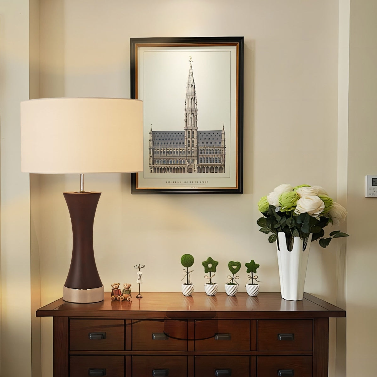 Decorative setup with a lamp, framed picture, and plants on a wooden console table.