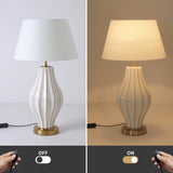 Table lamp with white shade and ribbed base, shown off and on with remote control.