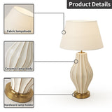 Table lamp with fabric lampshade, ceramic body, and brass holder on a white background