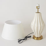 Table lamp with white shade and gold base on a light gray background