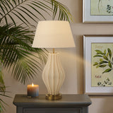 Table lamp on a side table with a candle and framed artwork in the background