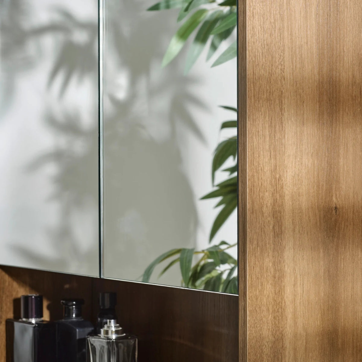 Bathroom setting with mirrors, bottles, and a the Hampshire wooden cabinet.