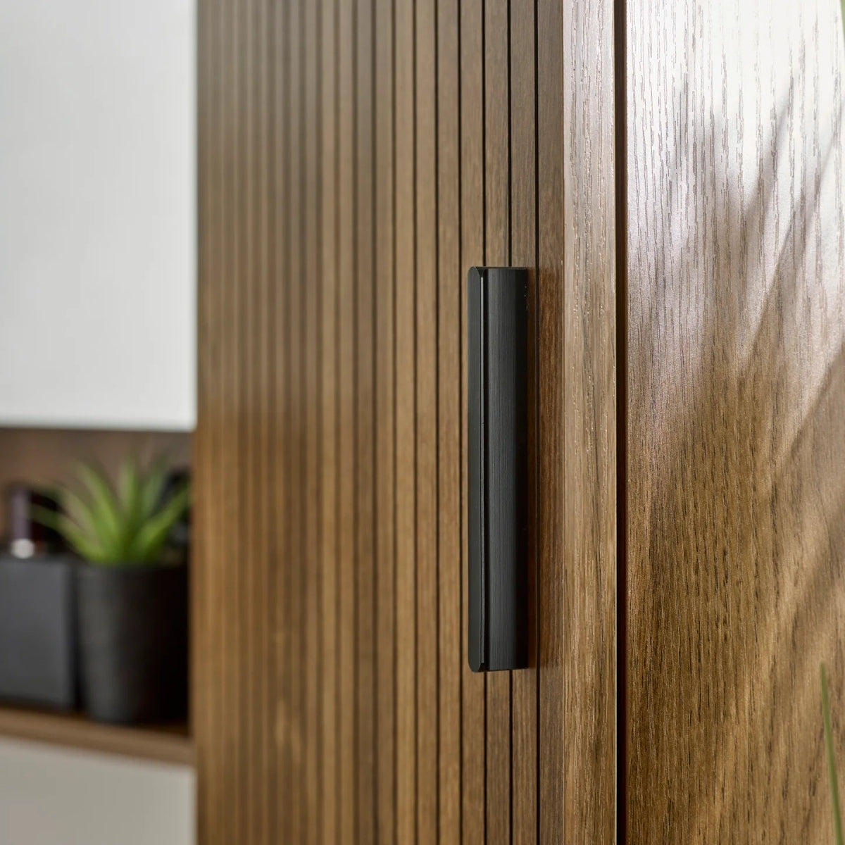 Close-up of the Hampshire wooden cabinet with a black handle, blurred background.