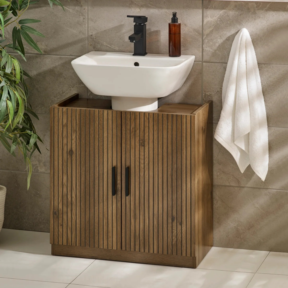 Hampshire bathroom setup with wooden cabinet, white sink, and towel on a tiled wall.