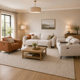 Modern living room with beige walls, white sofa, brown armchair, and wooden coffee table.
