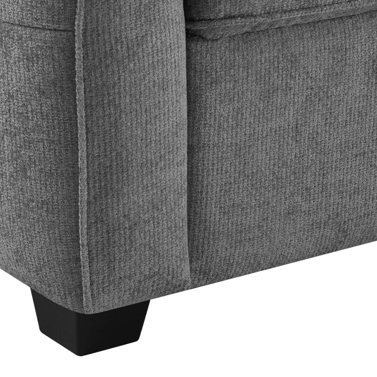 Close-up of the Keenan grey textured fabric sofa bed and side of an upholstered piece of furniture, showing a dark wood or metal leg on a white background.