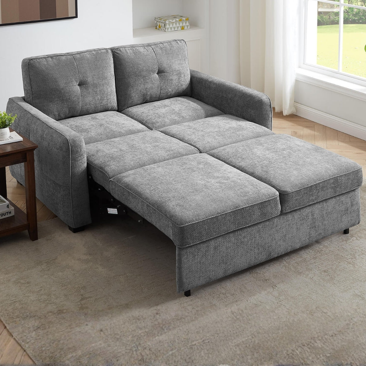 Keenan grey upholstered sofa bed with a chaise lounge section, shown partially extended in a bright living room with wood flooring and a window.