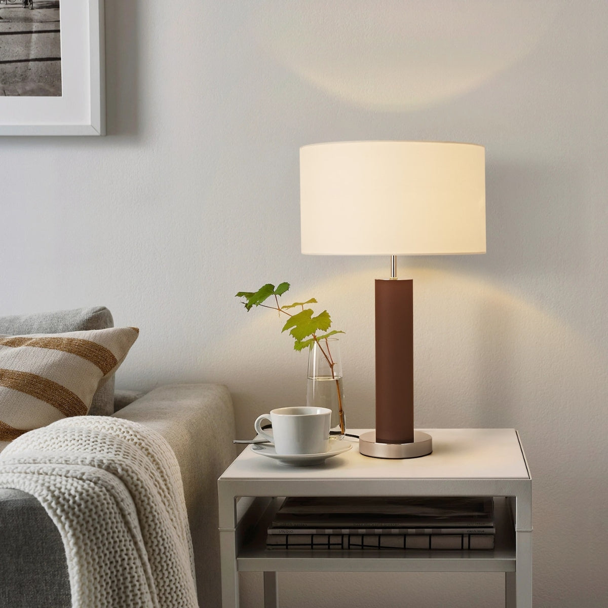Modern living room with a lamp on a side table, sofa, and framed picture.