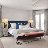 Modern bedroom with a large bed, bench, and lamps.
