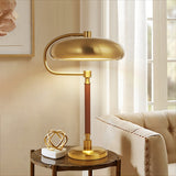 Gold table lamp on a side table with a beige sofa and framed artwork in the background