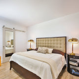 Neatly made bed in a bedroom with two lamps and a mirror.