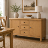Maldon oak wood sideboard or buffet cabinet with three drawers and two doors, styled in a warm dining room setting with a vase, books, a lamp, and a framed print.
