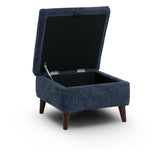 Manhattan navy blue upholstered storage ottoman with a hinged lid and dark brown tapered legs, shown open on a white background.