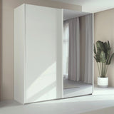Trixie white wardrobe with a mirror in a minimalistic room with a plant.