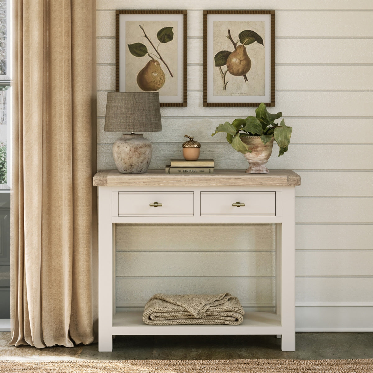 Wilson cream console table with oak top against a wall with framed artwork and decor items.