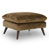 Zora ottoman with a thick cushioned top and dark tapered wooden legs, shown on a clean white background.