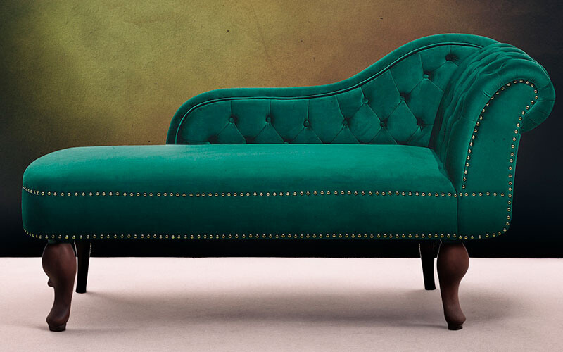 Green velvet chaise lounge with buttons and wooden legs.