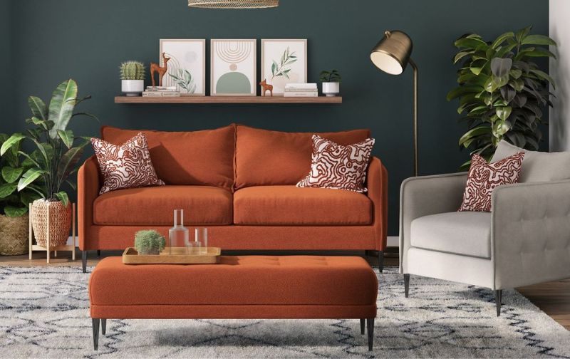 Orange standard sofa with matching ottoman, patterned cushions and grey feature chair. 