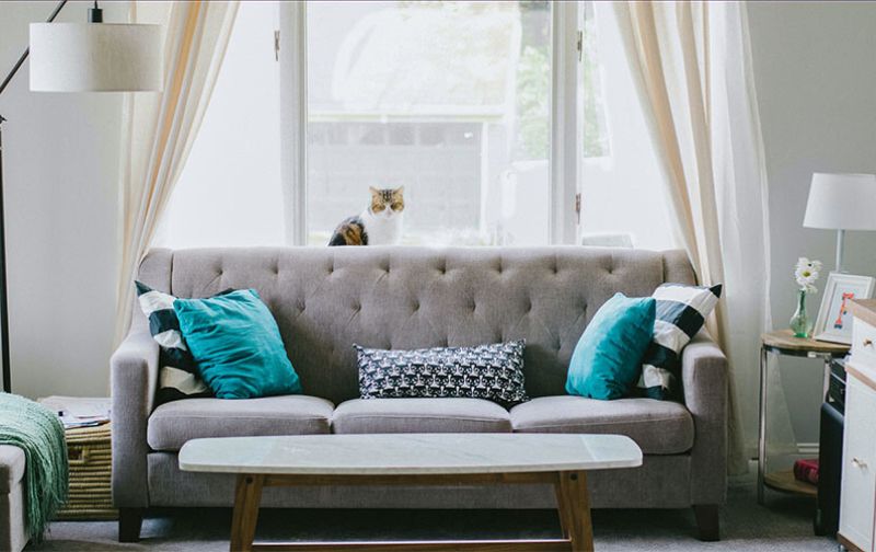 Small grey two seater sofa with cushions.