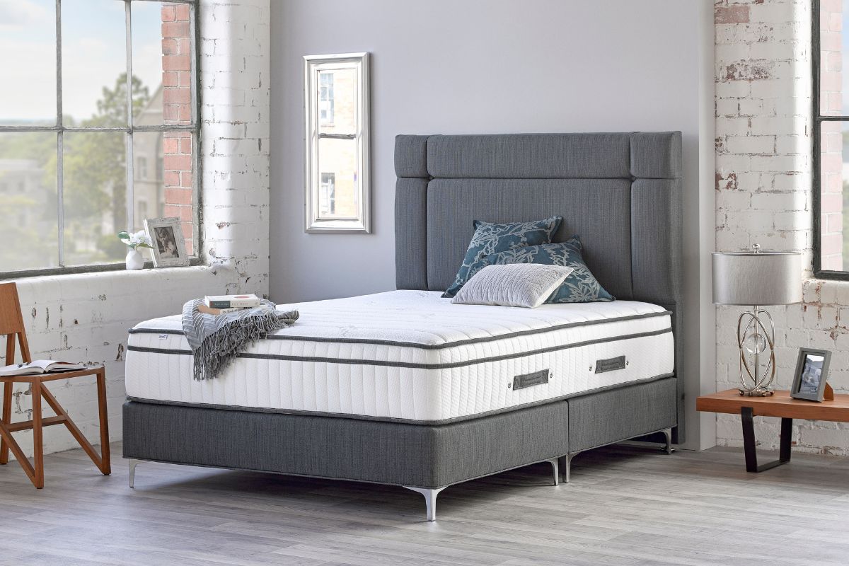 Grey fabric headboard and base with mattress.