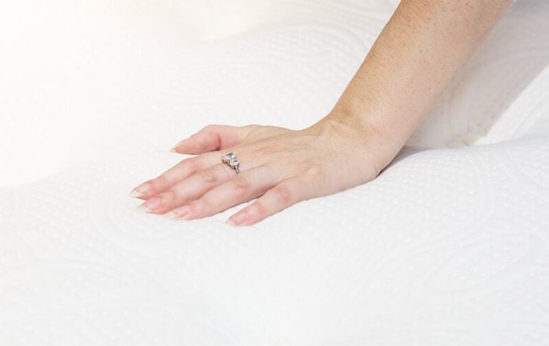 Woman's hand on mattress.