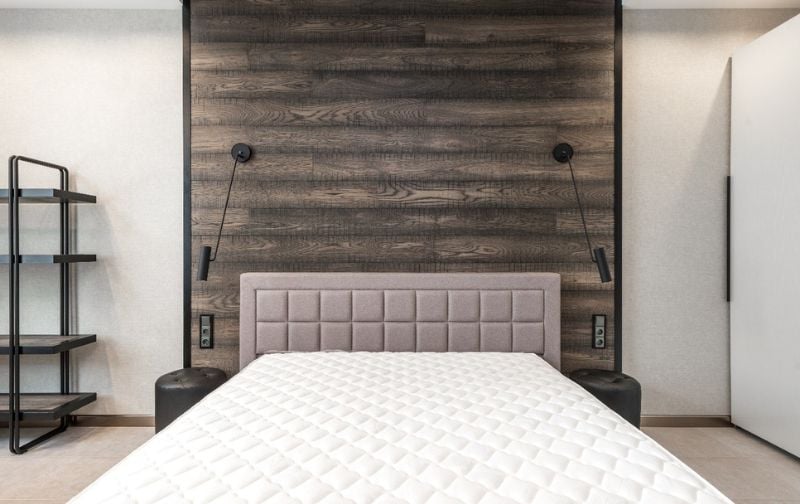 Quilted mattress against paneled headboard. 
