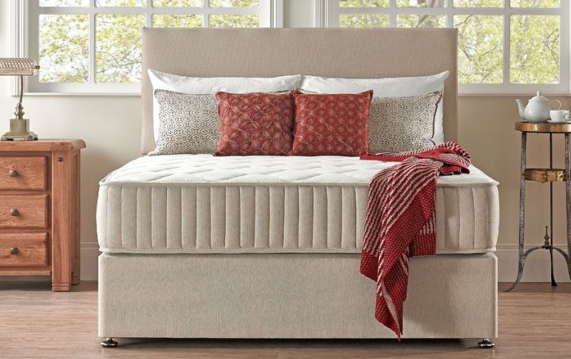 Cream pleated mattress with orange throw.