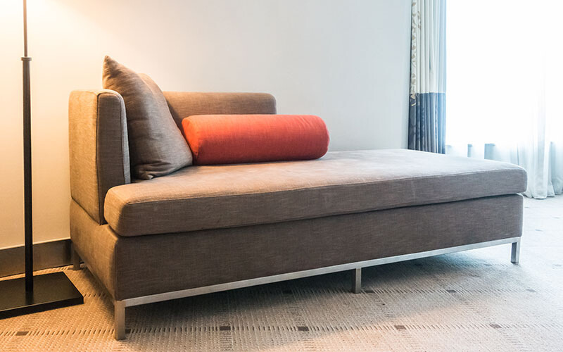 Contemporary grey chaise lounge with cushions.