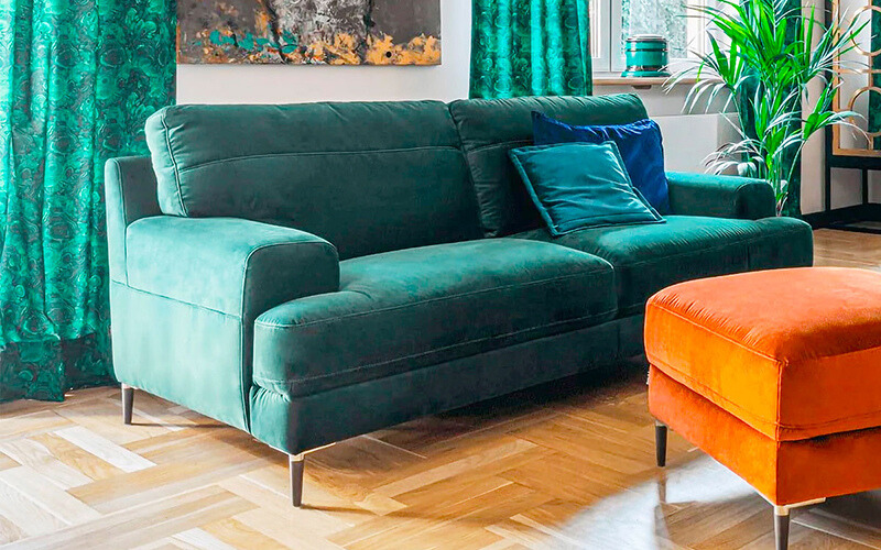 Green velvet sofa with cushions.