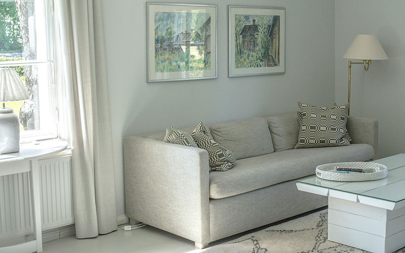 Grey fabric minimalist sofa in corner of a living room.