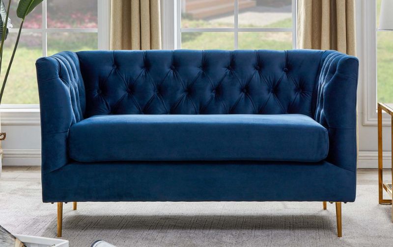 Navy velvet loveseat sofa against window backdrop with neutral curtains.