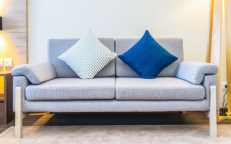 Modern light grey loveseat with wooden legs.