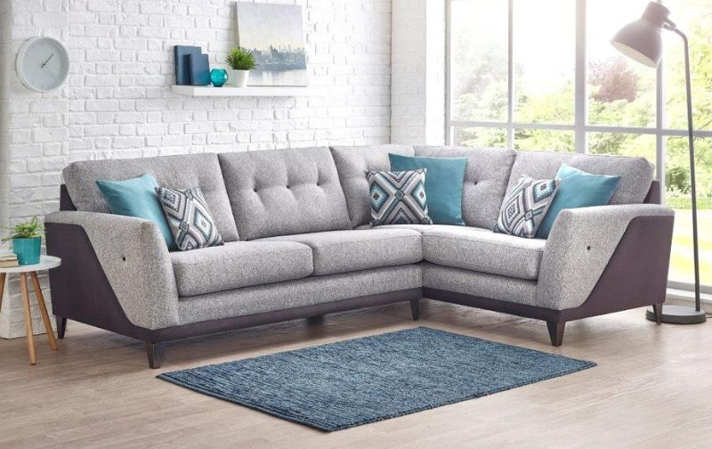 Traditional light grey corner sofa with patterned and teal scattered cushions and teal rug. 