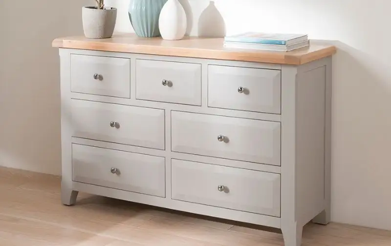 Traditional ivory chest of drawers with silver knobs and wooden surface. Traditional-ivory-chest-of-drawers-with-silver-knobs-and-wooden-surface