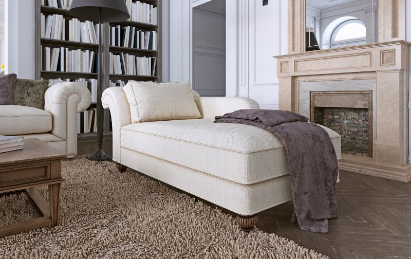 Cream fabric chaise lounge sofa with beige throw and neutral rug.