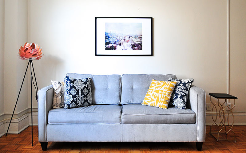 Grey minimalist loveseat sofa with orange lamp.