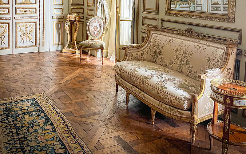 Ornate fabric loveseat with gold gilded legs.