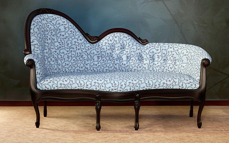 Light blue patterned fabric chaise lounge with wooden detailing and wooden legs.