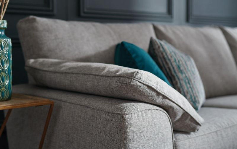 Light grey fabric covered sofa corner with scattered cushions.