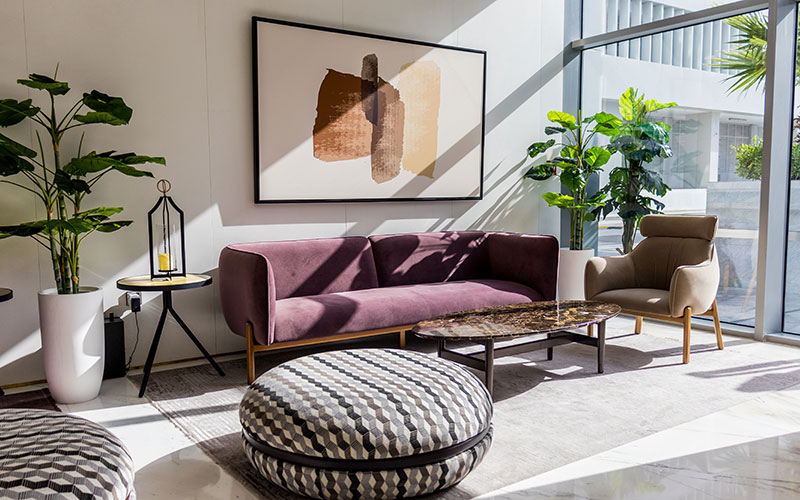 Purple velvet minimalist sofa with wooden legs and feature ottoman.