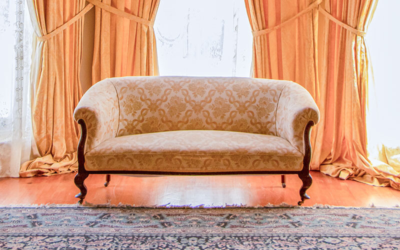 Traditional loveseat with patterned fabric and wooden legs.