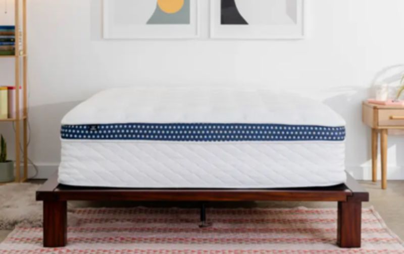 Quilted mattress with navy polka dot feature on wooden legs.
