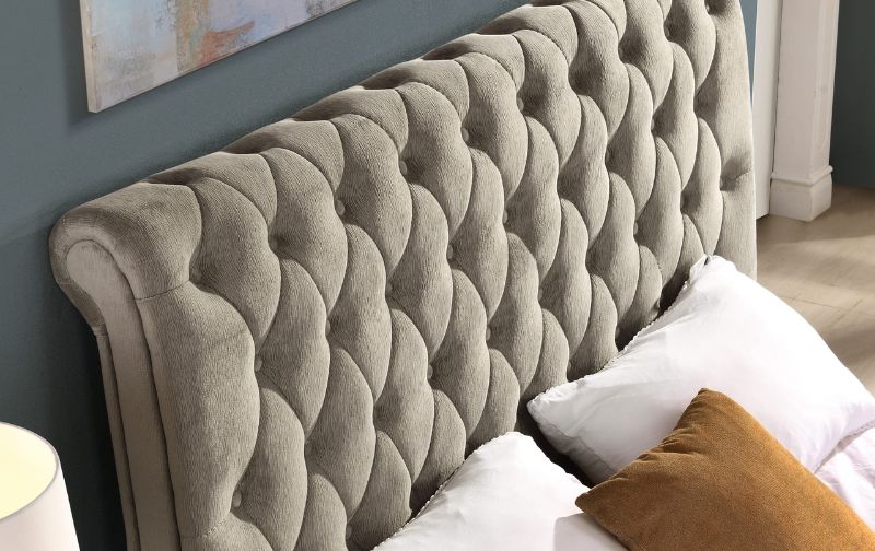 Grey tufted fabric headboard with buttons.
