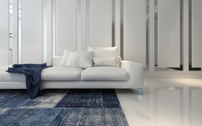 a white couch in a large room with a dark coloured blue rug